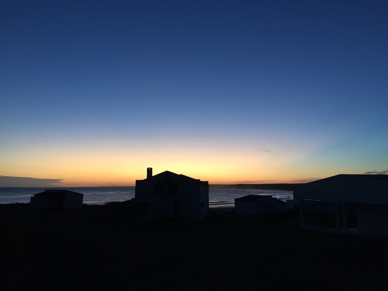 sunset, sea, horizon over water, copy space, architecture, built structure, building exterior, water, clear sky, silhouette, scenics, orange color, tranquil scene, tranquility, beach, beauty in nature, sky, nature, blue, shore