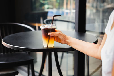 Cropped hand of woman holding drink on table