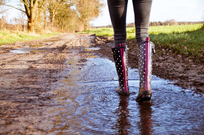 Low section of woman walking on dirt road