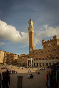 Group of people in front of historical building against sky
