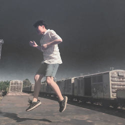 Side view of young man jumping in city