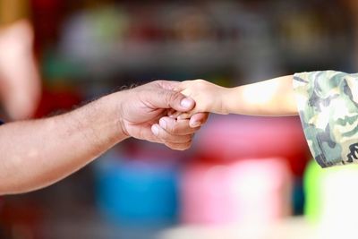 Cropped image of father holding child hand outdoors