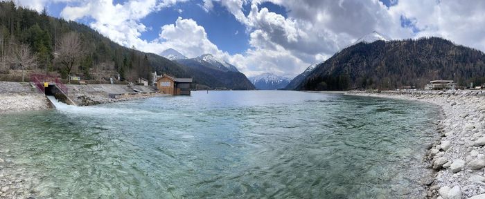 Panoramic view of sea by mountains against sky