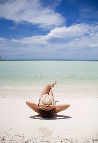 Woman lying on beach against sky