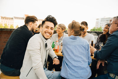 Portrait of happy man sitting with friends and enjoying at social gathering