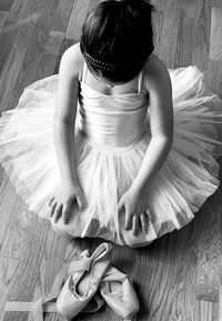 High angle view of girl with ballet shoes kneeling on floor