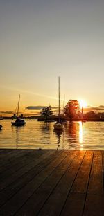 Boats moored at harbor during sunset