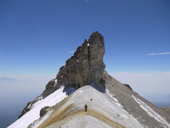 Man hiking on mountain peak against sky