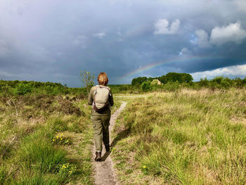 Rear view of man standing on field against sky