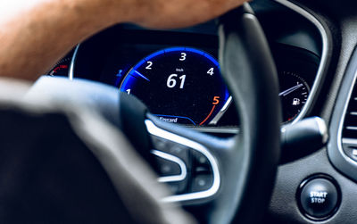 Close-up of hand holding steering wheel while driving a car