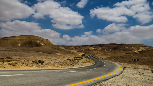 Road leading towards mountains against sky