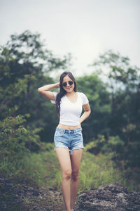 Full length portrait of young woman standing on land against clear sky