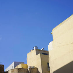 Low angle view of buildings against clear blue sky