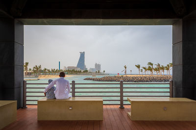 Rear view of people sitting on seat in city