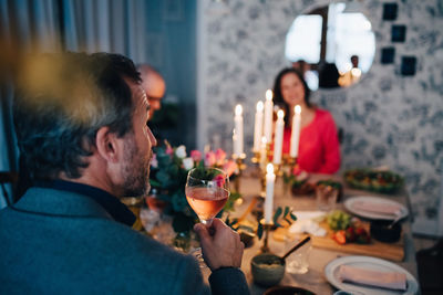 Mature man having wine while sitting with friends at dinner party