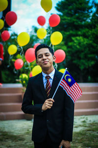 Portrait of a boy holding flag while standing at park