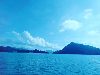 Scenic view of sea and mountains against blue sky