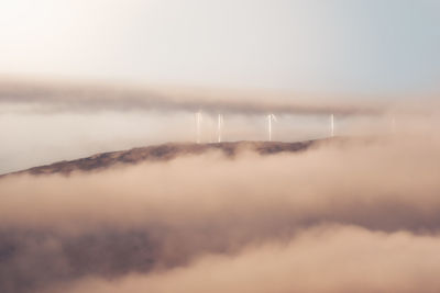 Windmills of modern wind power station located on hill in misty morning in countryside