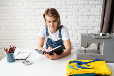 Portrait of woman using mobile phone while sitting on table