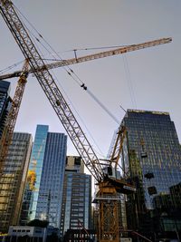 Cranes in city against sky