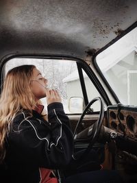 Side view of young woman driving car