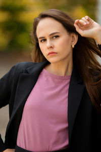 Young woman in black trouser suit and pink t-shirt on the background of the park