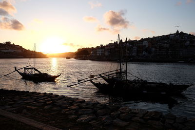 Silhouette boats in sea against sky during sunset