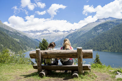 Rear view of friends looking at mountains while sitting on seat