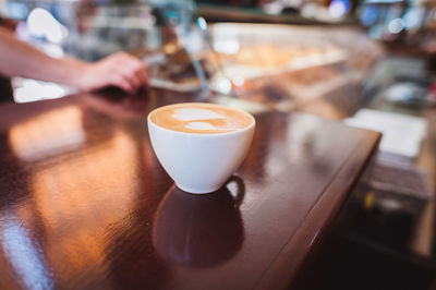 Cropped hand of man by coffee on table at store