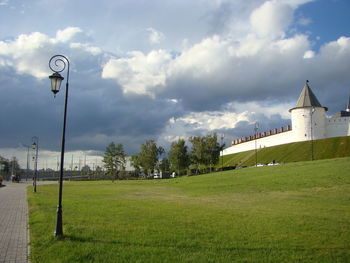 Scenic view of field by buildings against sky