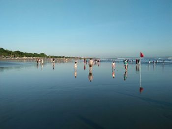 Group of people on beach against clear sky