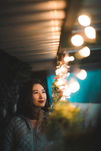 Woman looking at illuminated string lights at night