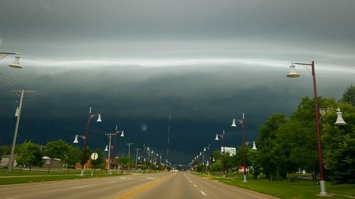 Road by trees against sky
