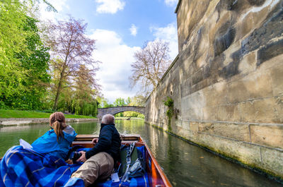 People sitting on boat by river against sky