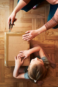 Woman unpacking a cardboard box parcel in room at home. little girl waiting for opening a box