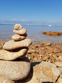 Stack of pebbles in sea against sky