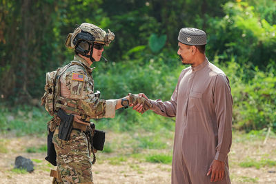 Side view of soldier shaking hand with man outdoors