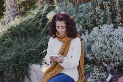 Young woman looking away while standing on snow covered land