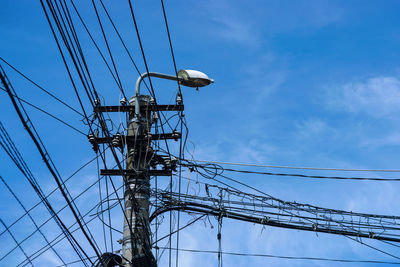 Low angle view of electricity pylon against blue sky