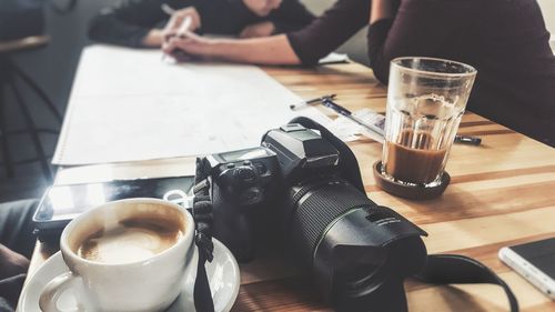 Close-up of camera against people discussing paperwork on table