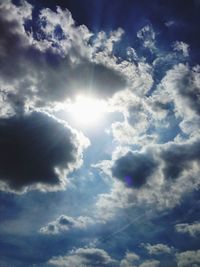Low angle view of sunlight streaming through clouds