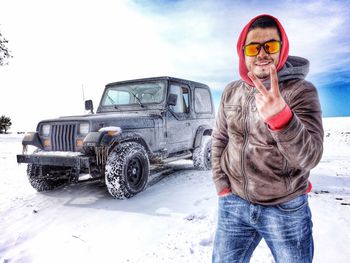 Portrait of man beside off-road car in winter