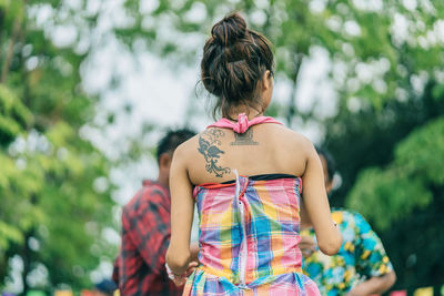 Rear view of woman standing against trees