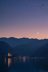 Scenic view of lake and mountains against clear sky at sunset