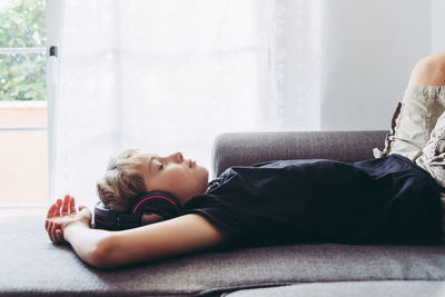 Boy listening music while sleeping on sofa at home