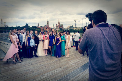 Rear view of people standing against buildings in city