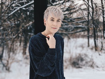 Portrait of thoughtful young woman standing in forest during winter