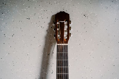 Close-up of guitar on table against wall