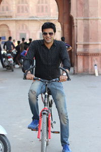 Portrait of smiling young man riding bicycle in city