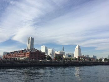 River by modern buildings against sky in city